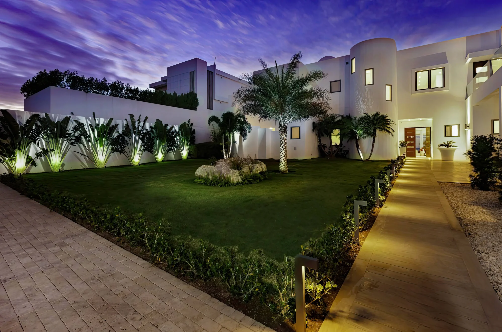 Luxury Anguilla beach house at dusk, showcasing tropical landscaping and elegant architecture.