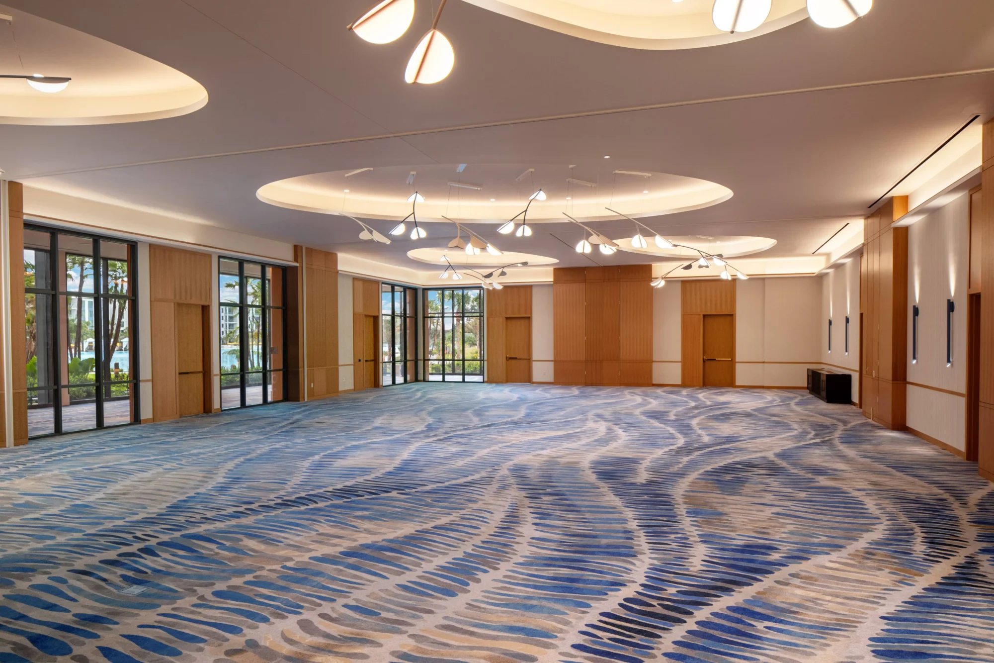 Spacious ballroom at Conrad Orlando, an Orlando wedding destination, with wave-patterned carpet and modern lighting.