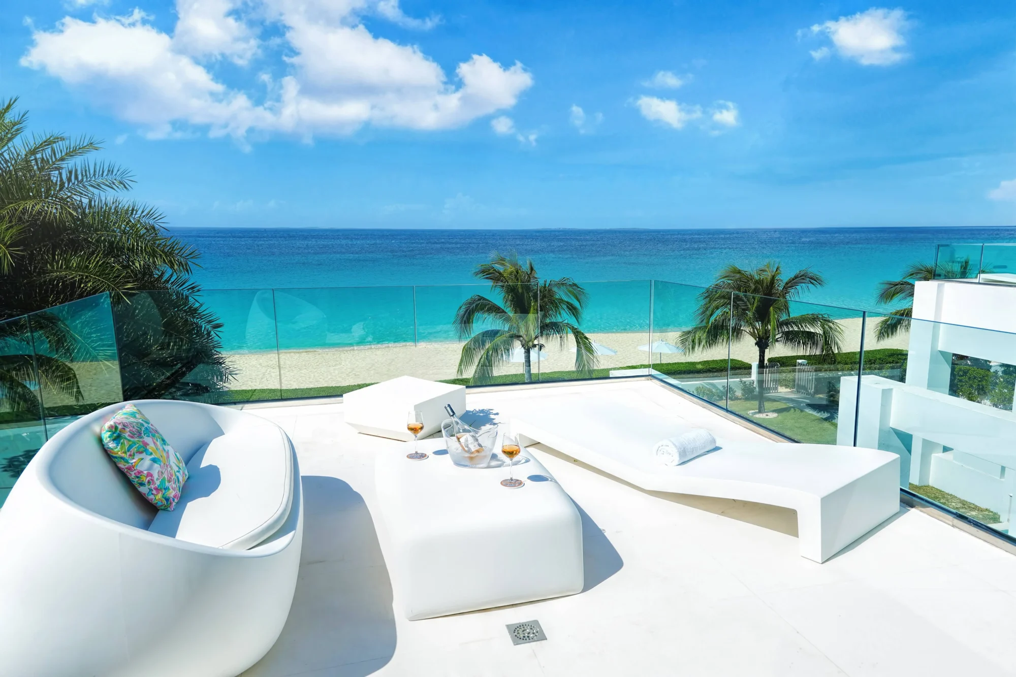 Luxury Anguilla beach house patio with ocean view, white furniture, and champagne.