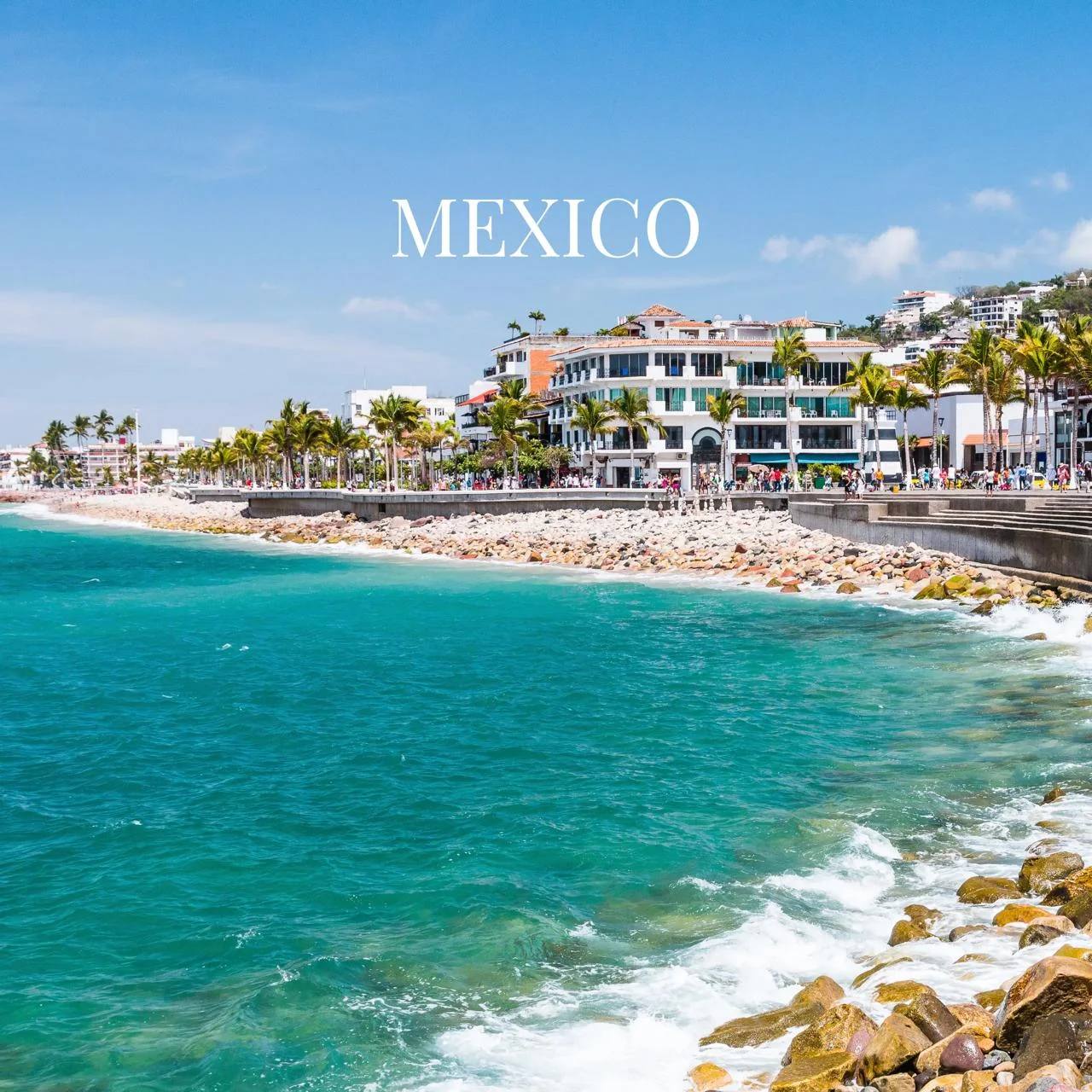 Vibrant turquoise ocean waves lapping a rocky shore in Mexico, with palm trees and white buildings along the coast.