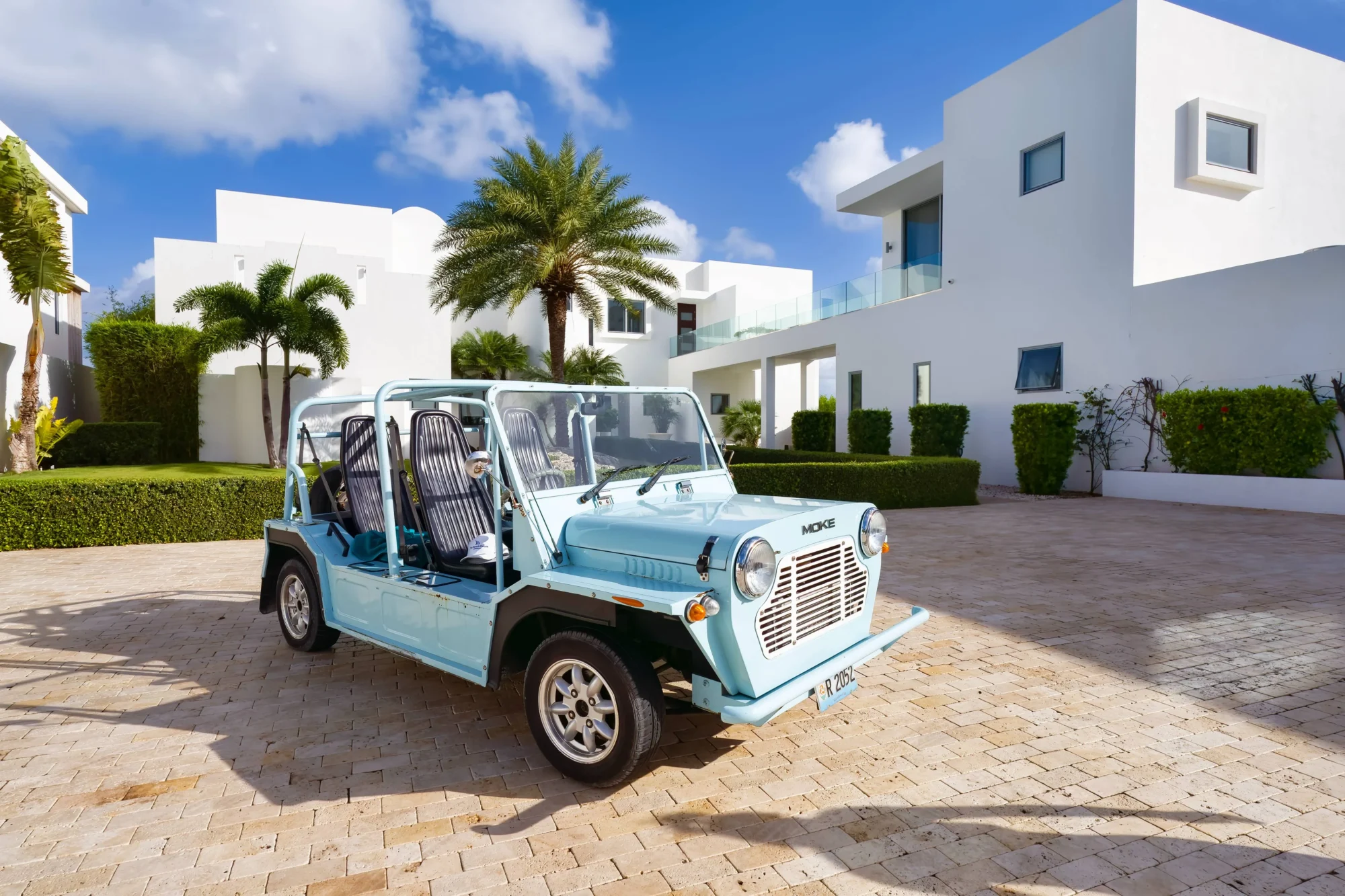 Light blue Moke car parked in front of a modern white Anguilla villa.