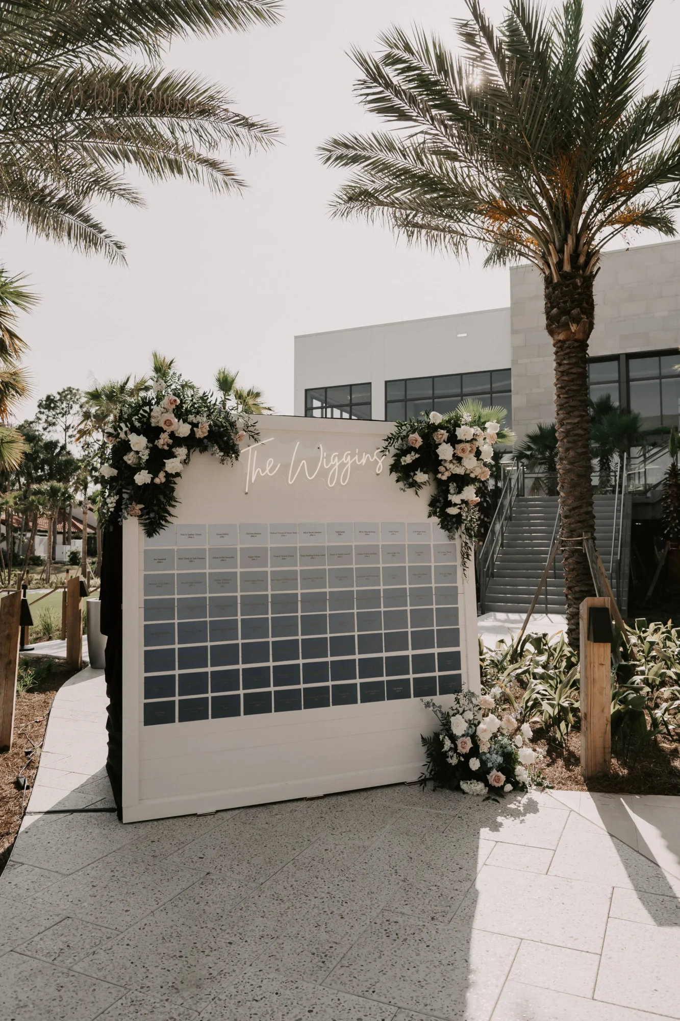 Wedding seating chart at The Wiggins wedding, an Orlando wedding destination, with floral arrangements and palm trees.