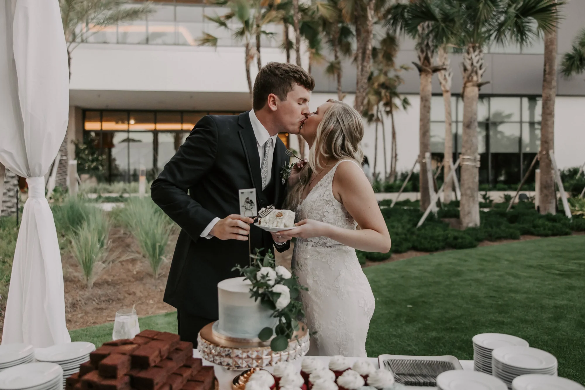 Newlyweds share a kiss while cutting their wedding cake at an Orlando wedding destination