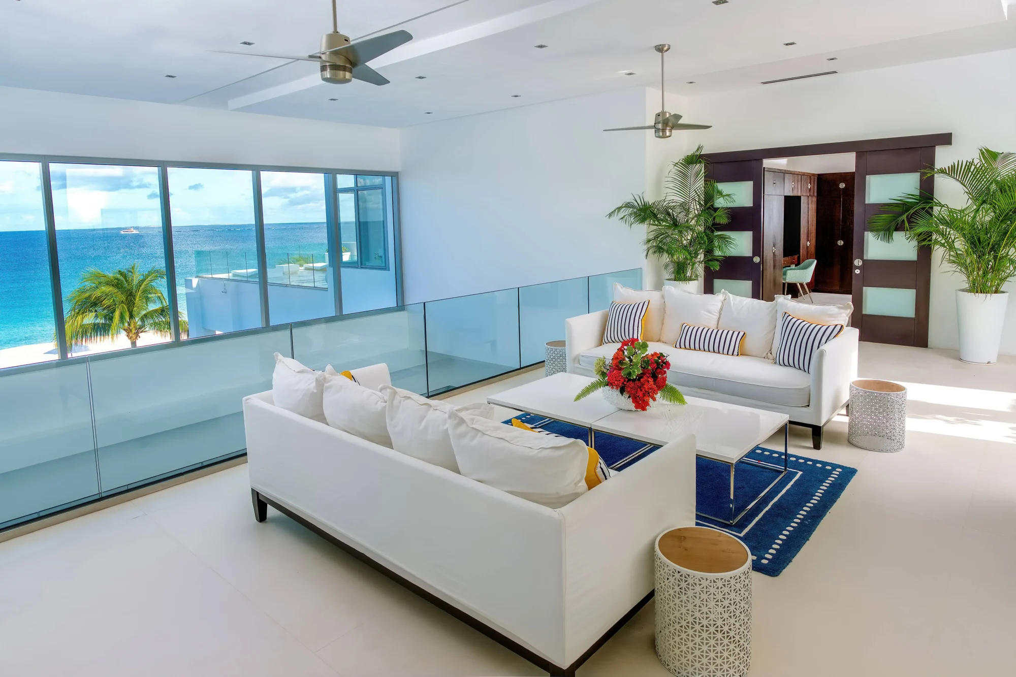 Luxury Anguilla beach house living room with ocean view. White sofas and blue rug.