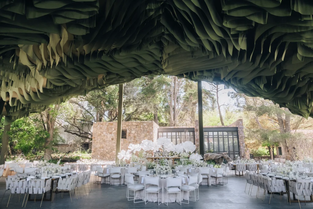Elegant Dream Wedding in Mexico: Tables set under a unique, draped ceiling with white floral centerpieces.