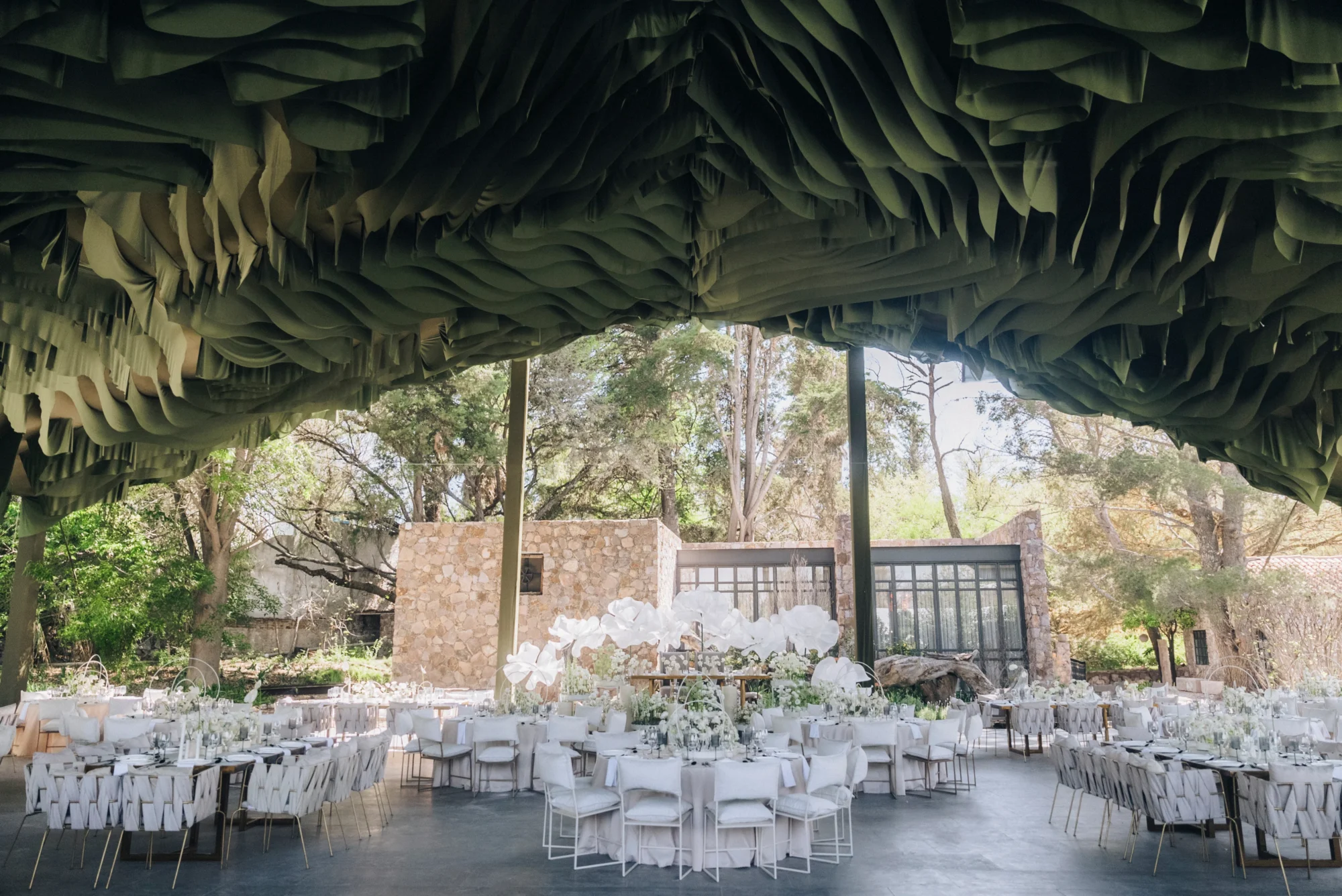 Elegant Dream Wedding in Mexico: Tables set under a unique, draped ceiling with white floral centerpieces.