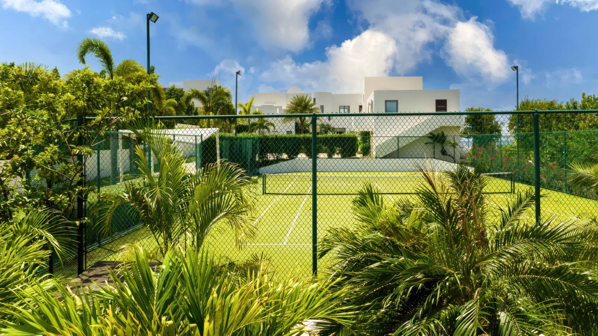 Luxury Anguilla resort tennis court, surrounded by tropical landscaping.