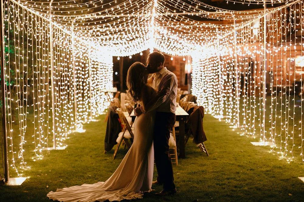 Couple kissing under string lights at a Jackson Hole Wyoming wedding at Bentwood Inn