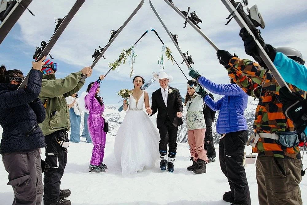 Bride and groom walk under skis at a Jackson Hole Wyoming wedding.