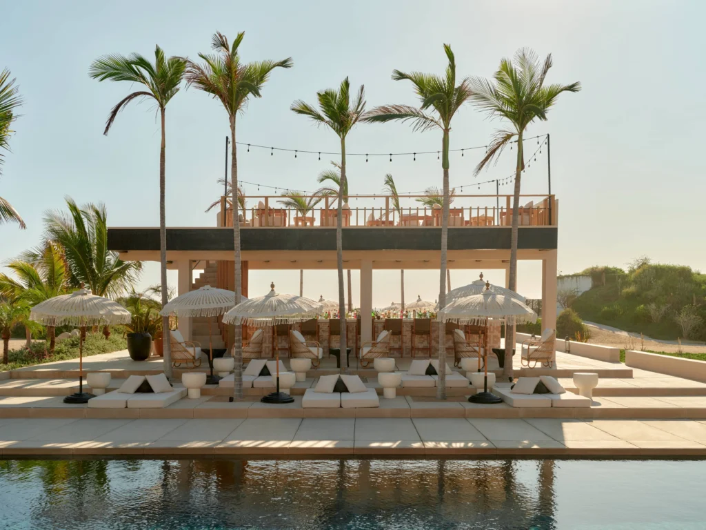 Luxury resort with pool, lounge chairs, and palm trees at Kimpton Mas Olas, a Mexican wedding destination.