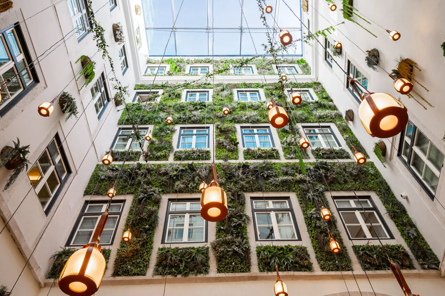 Interior courtyard at Palácio Ludovice Hotel, featuring a lush green wall and hanging lights.