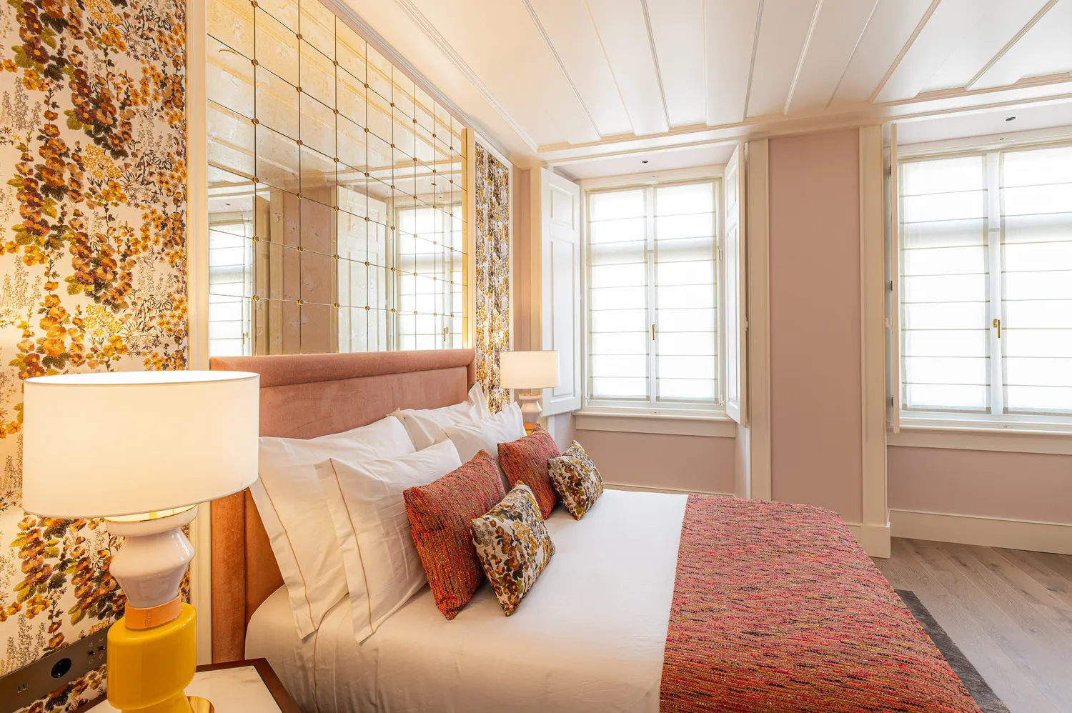 Luxurious bedroom at Palácio Ludovice Hotel featuring a mirrored headboard and colorful bedding.