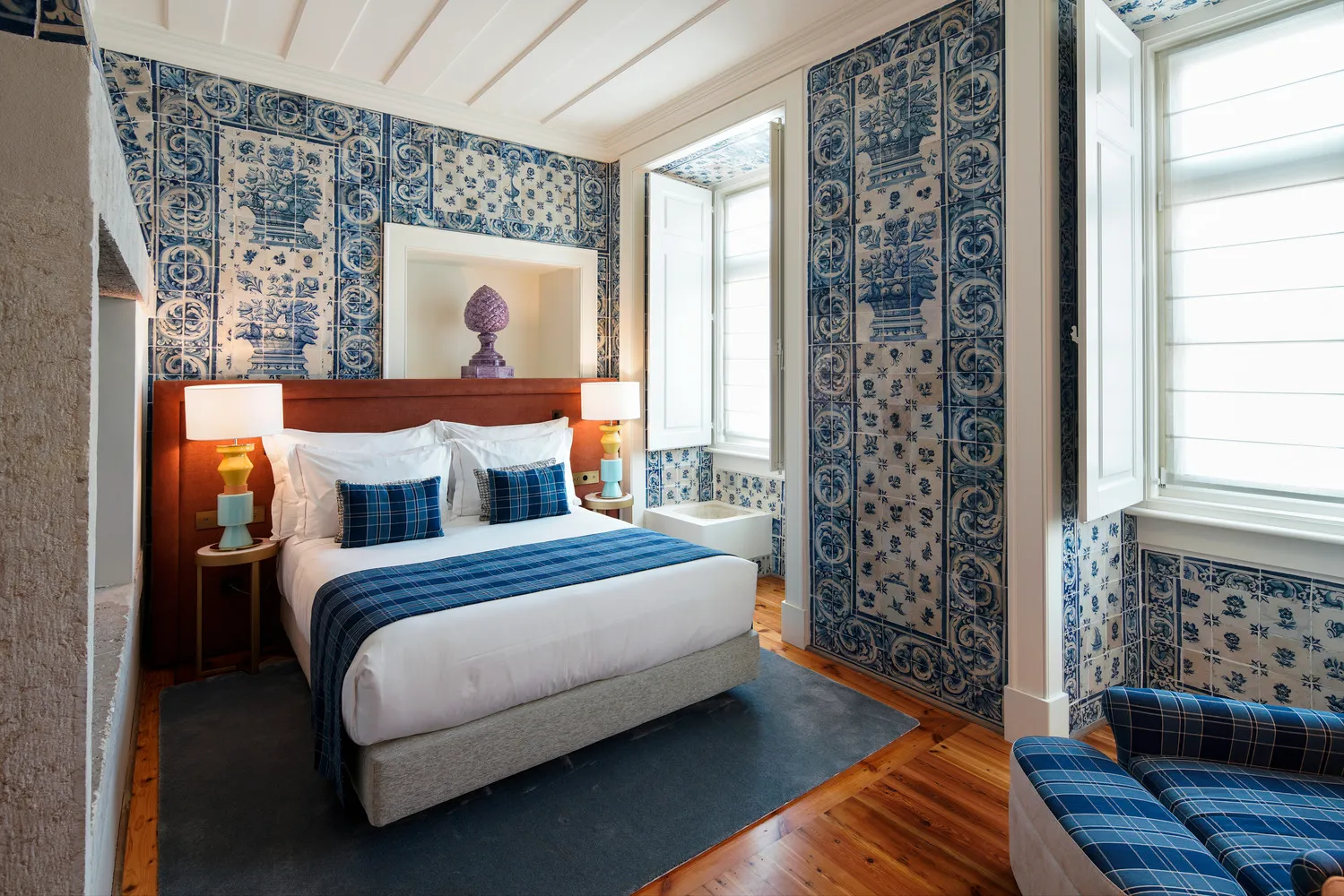 Luxurious bedroom at Palácio Ludovice Hotel, featuring a comfortable bed and stunning azulejo tile walls.