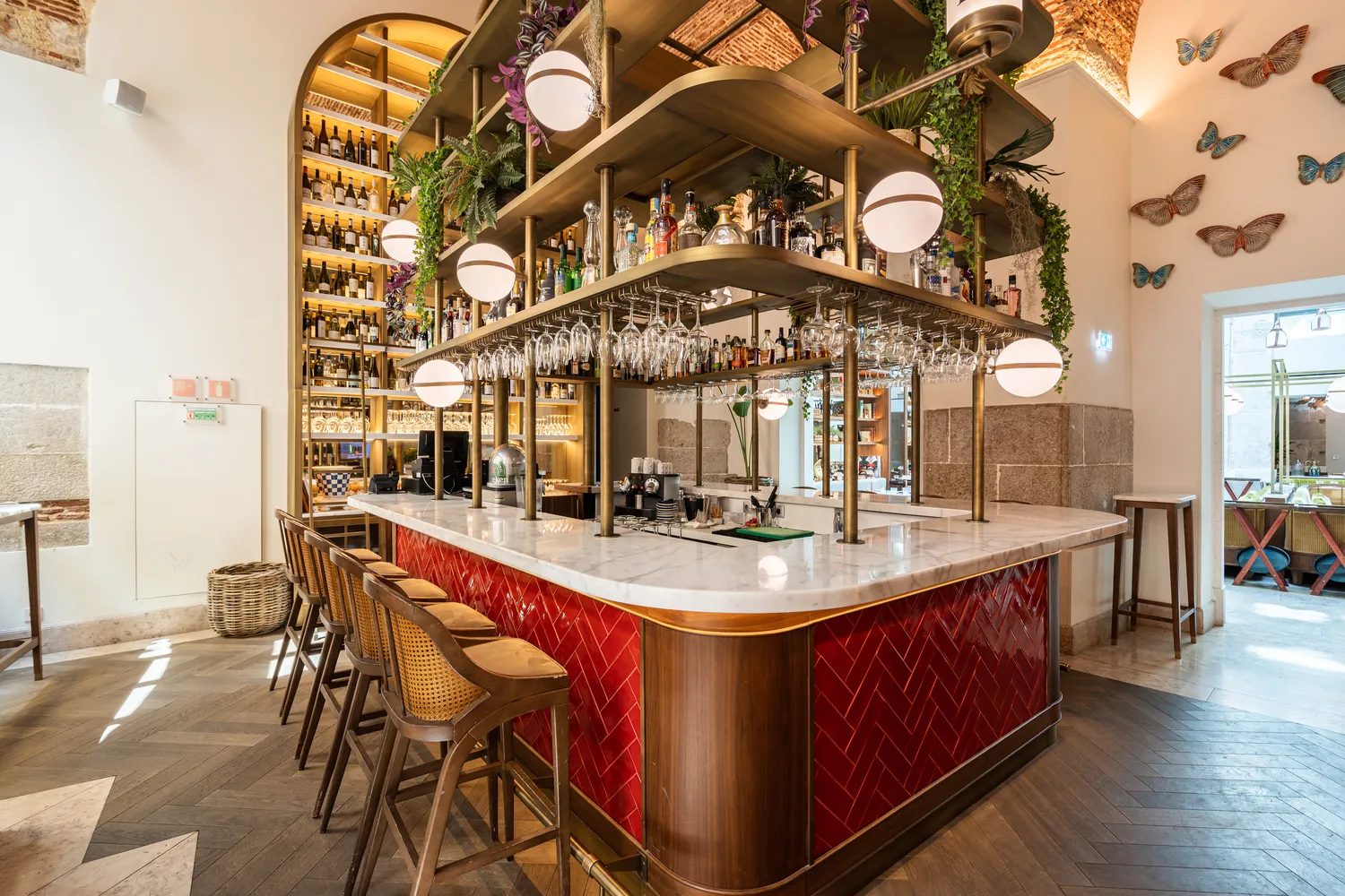 Elegant bar at Palácio Ludovice Hotel with marble top, red tile, and brass shelving.