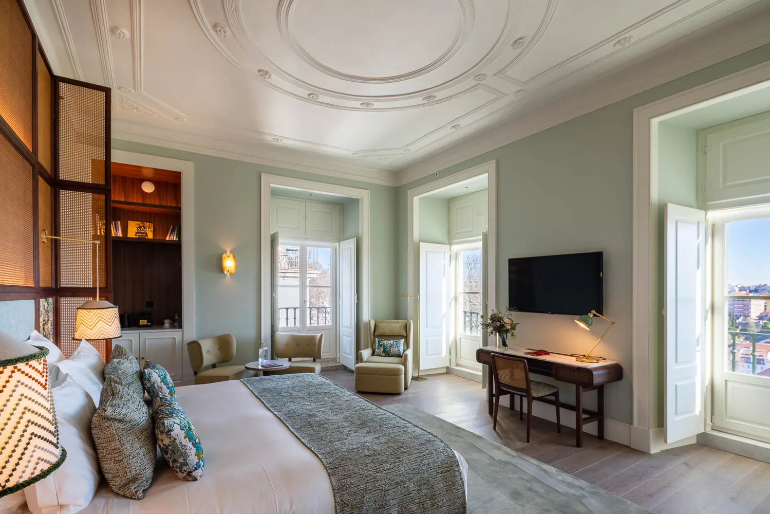 Luxurious Palácio Ludovice hotel suite with king bed, city view, and writing desk.