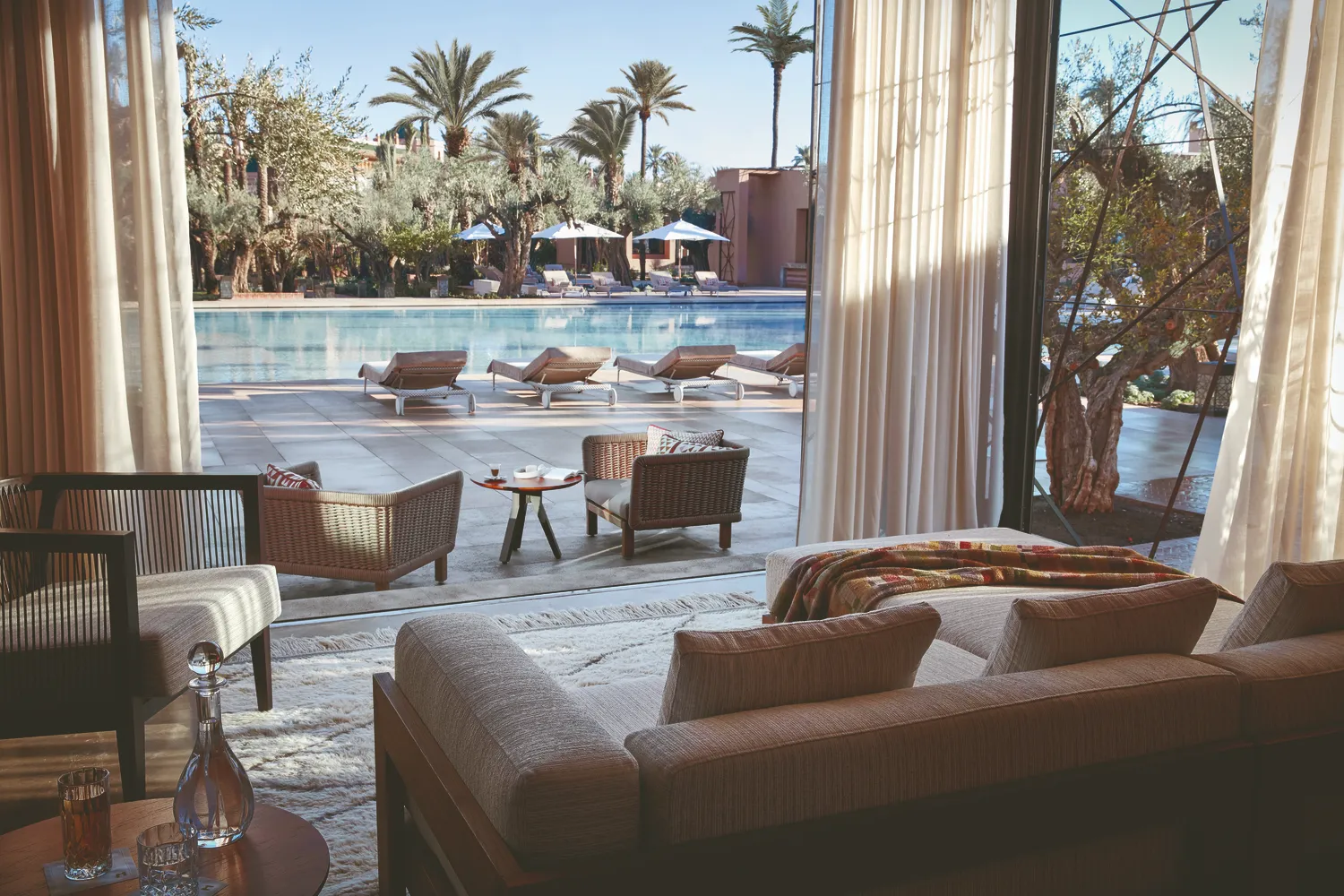 Luxury suite at Royal Mansour Marrakech overlooking a pool and palm trees.