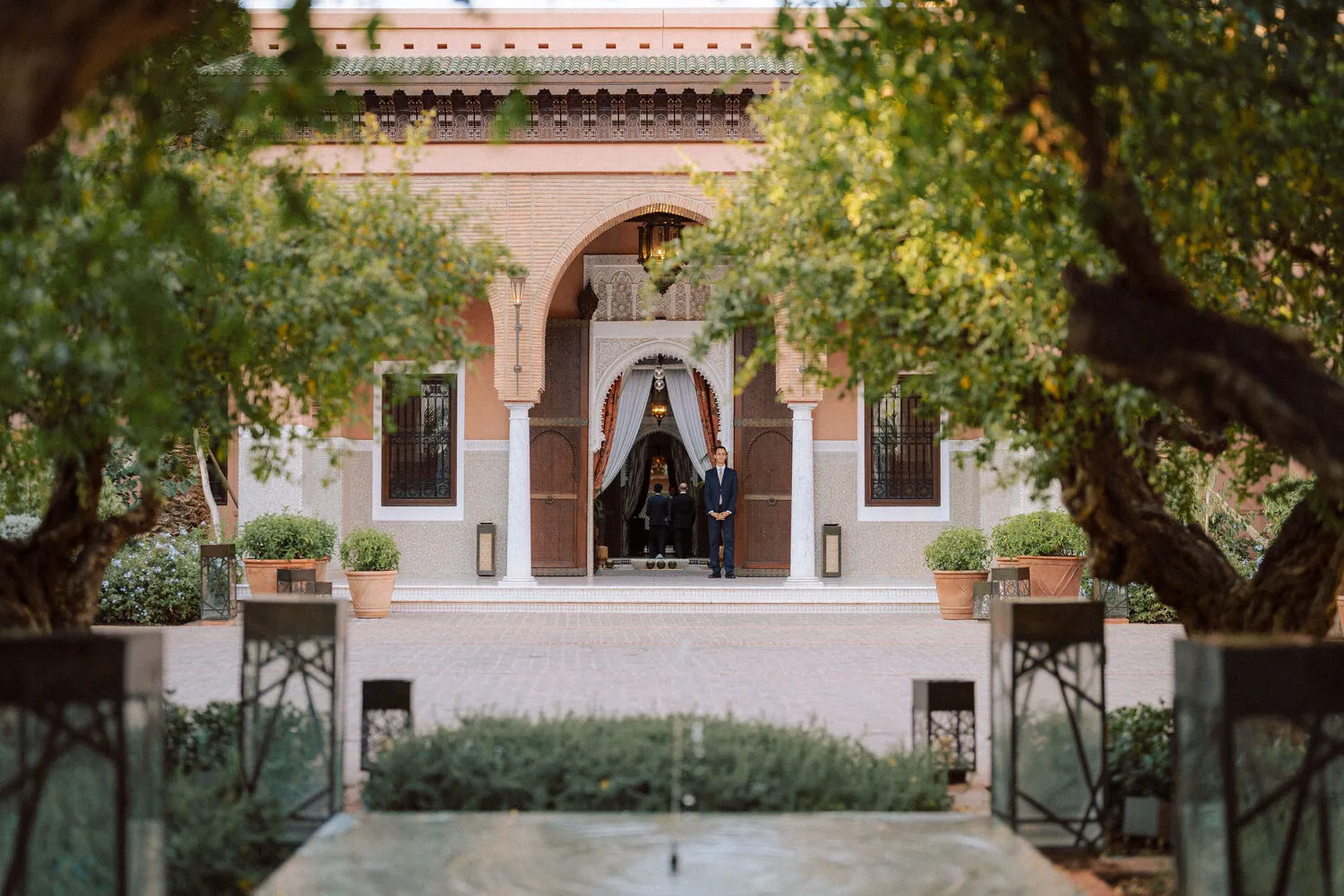 Grand entrance to Royal Mansour Marrakech, featuring a doorman and lush landscaping. Celebrations.