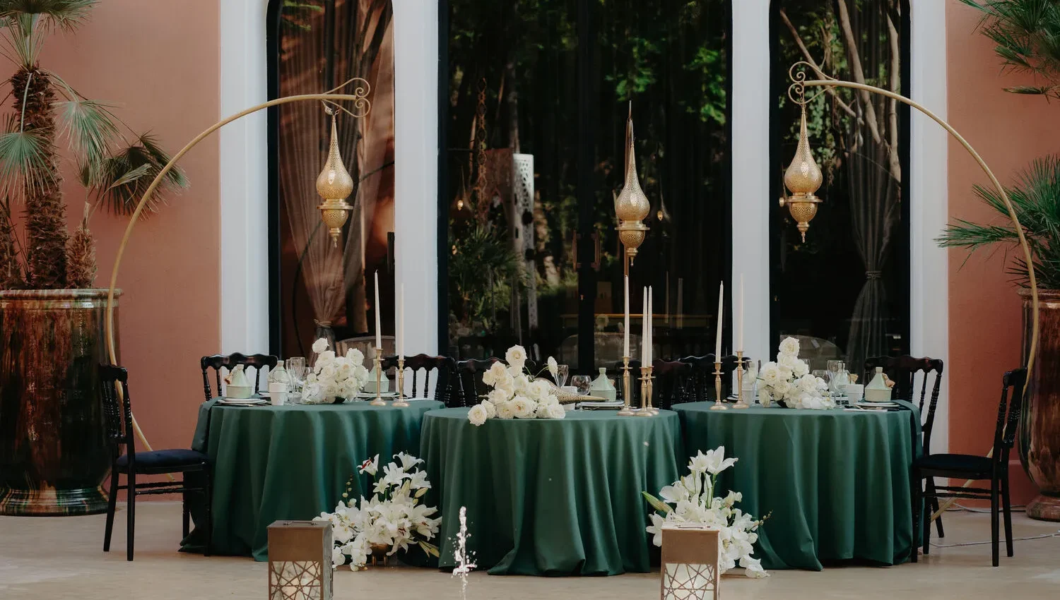 Elegant tablescape at a Royal Mansour Marrakech celebration, featuring green linens, white flowers, and gold lanterns.