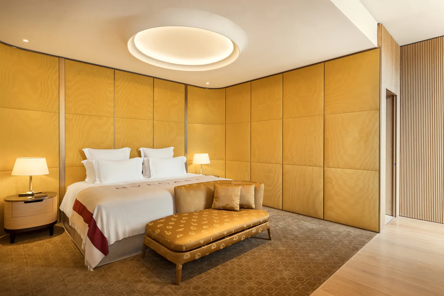 Luxurious Bvlgari Hotel Roma bedroom with king-size bed and chaise lounge.