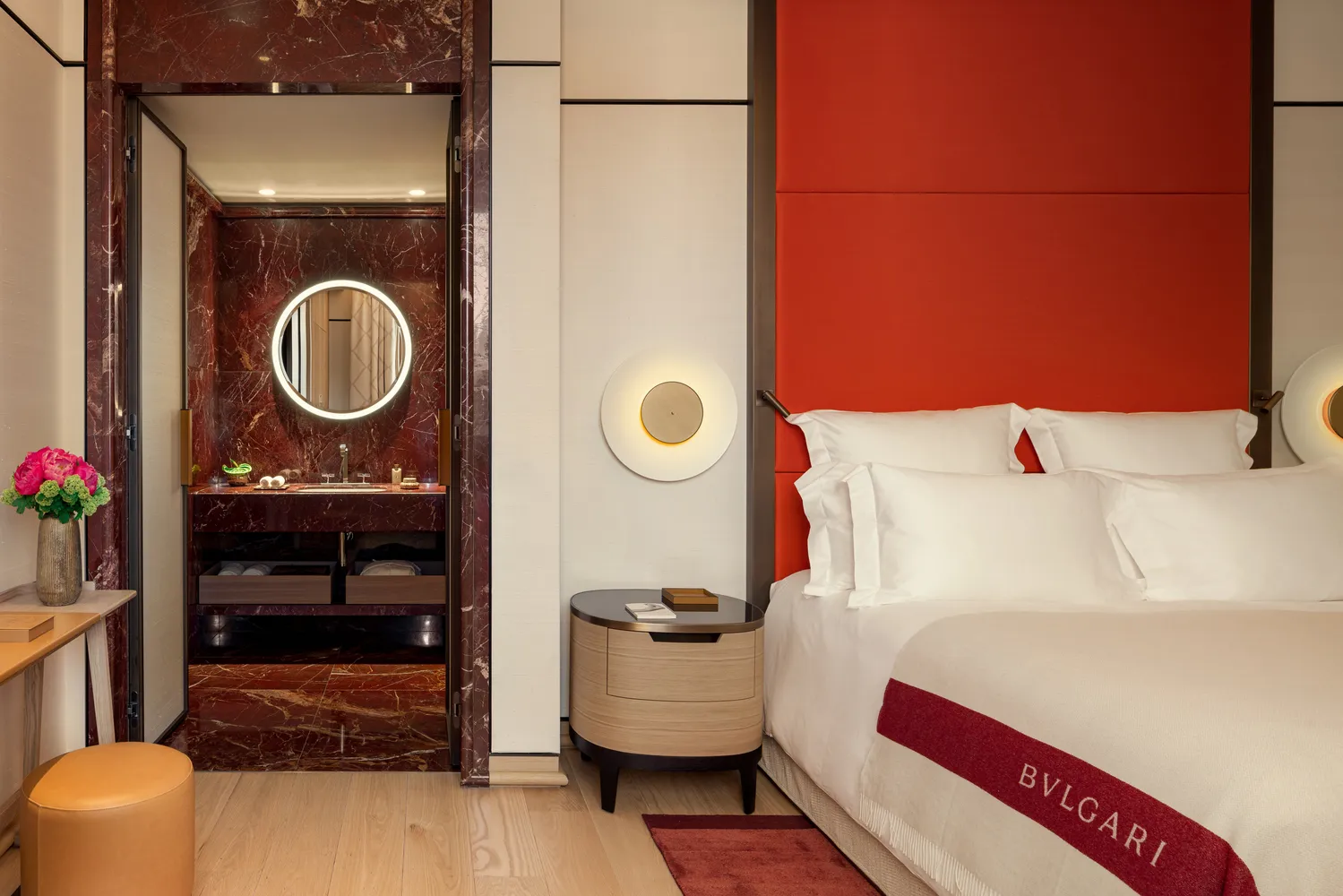 Luxurious Bvlgari Hotel Roma bedroom with red headboard and marble bathroom.
