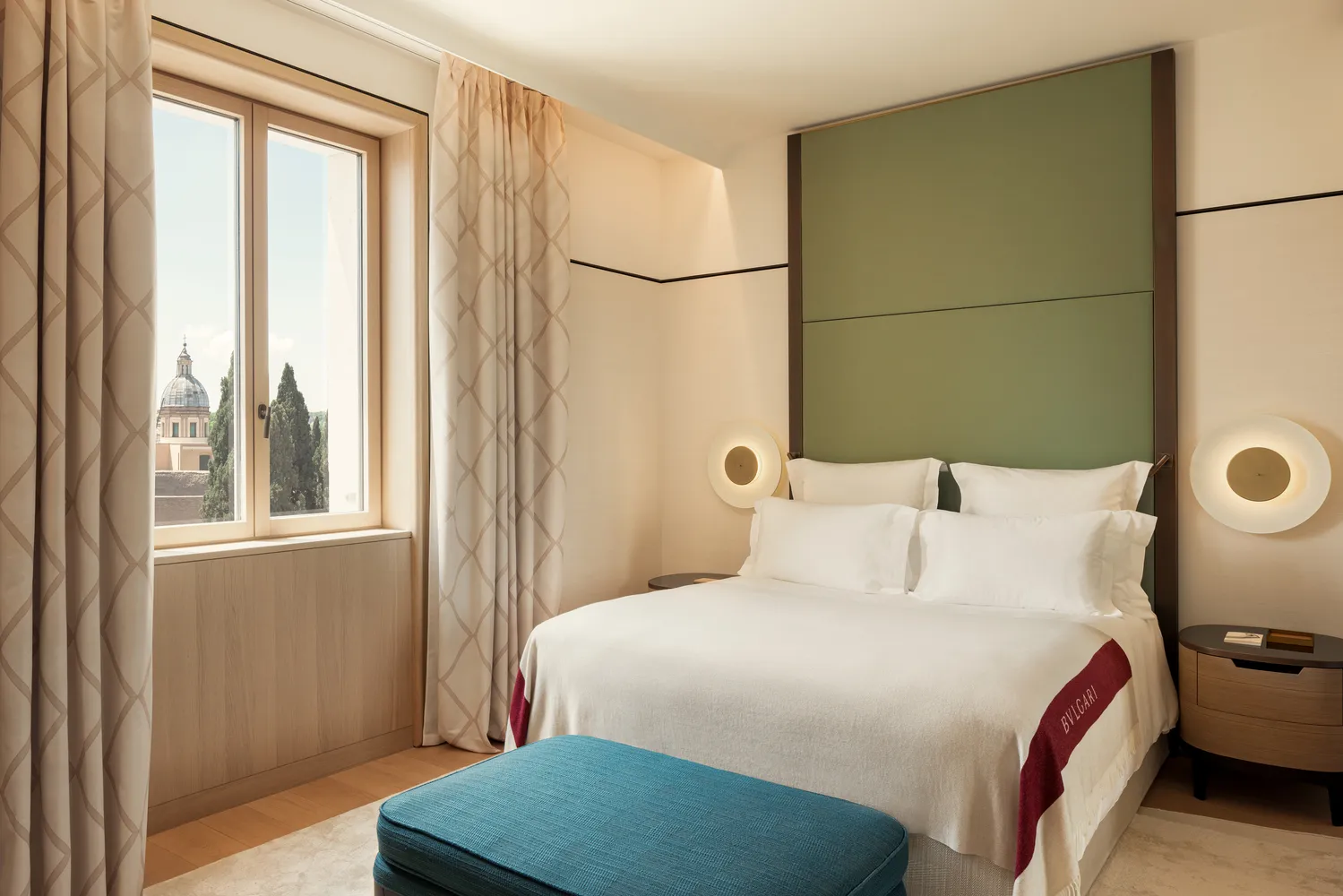 Luxury bedroom at the Bvlgari Hotel Roma, featuring a plush bed and city view.