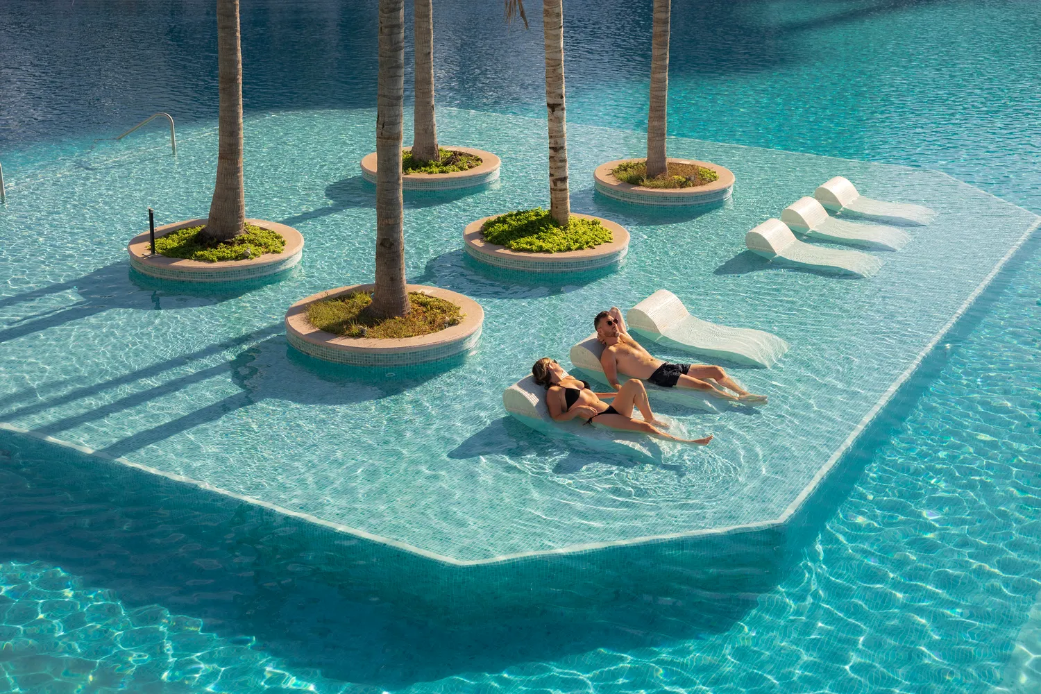 Couple relaxing on floating loungers in a luxurious Puerto Vallarta pool at the Marriott Resort.