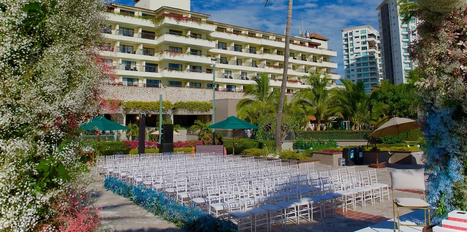 Outdoor wedding ceremony setup at Marriott Puerto Vallarta Resort & Spa. White chairs face a floral archway. Destination wedding in Puerto Vallarta.