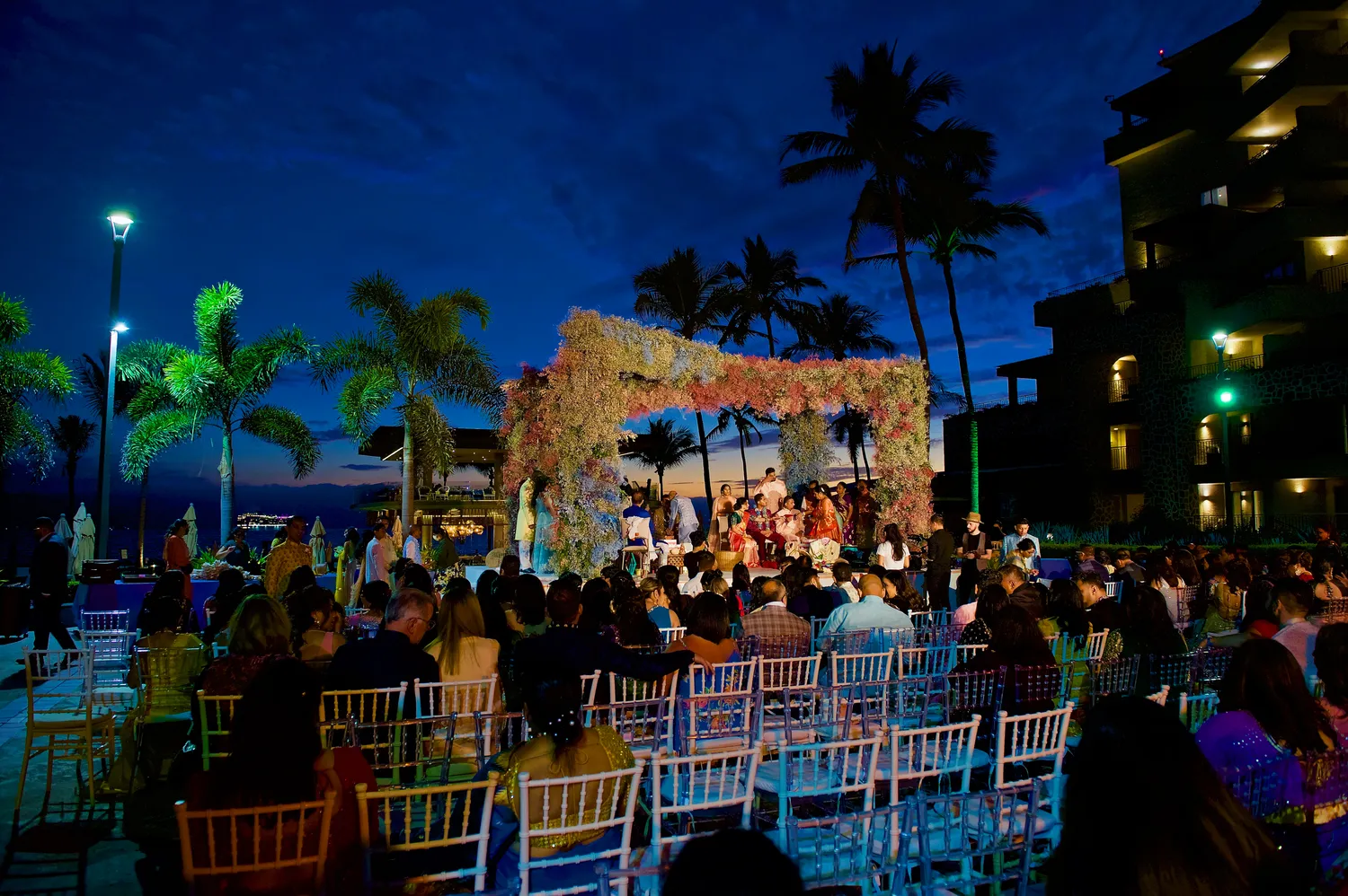 Destination wedding ceremony at sunset, Marriott Puerto Vallarta. Guests seated, floral arch.