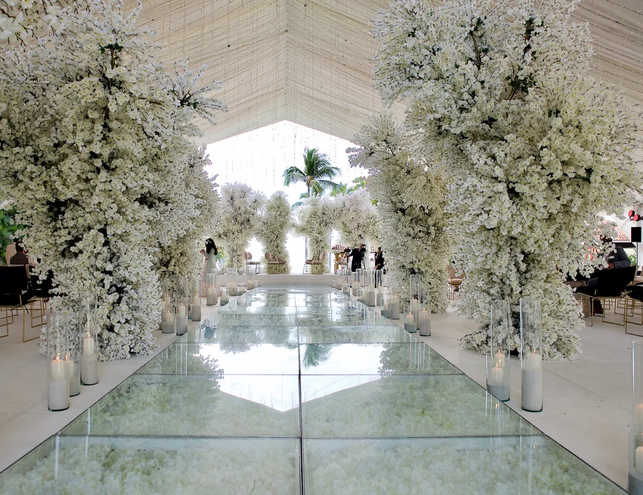 Glass aisle lined with white floral trees and candles at a destination wedding in Puerto Vallarta.