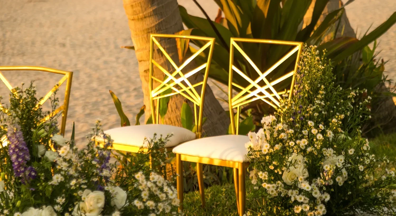 Two gold chairs with white cushions sit amidst flowers, a beautiful setting for a destination wedding in Puerto Vallarta.