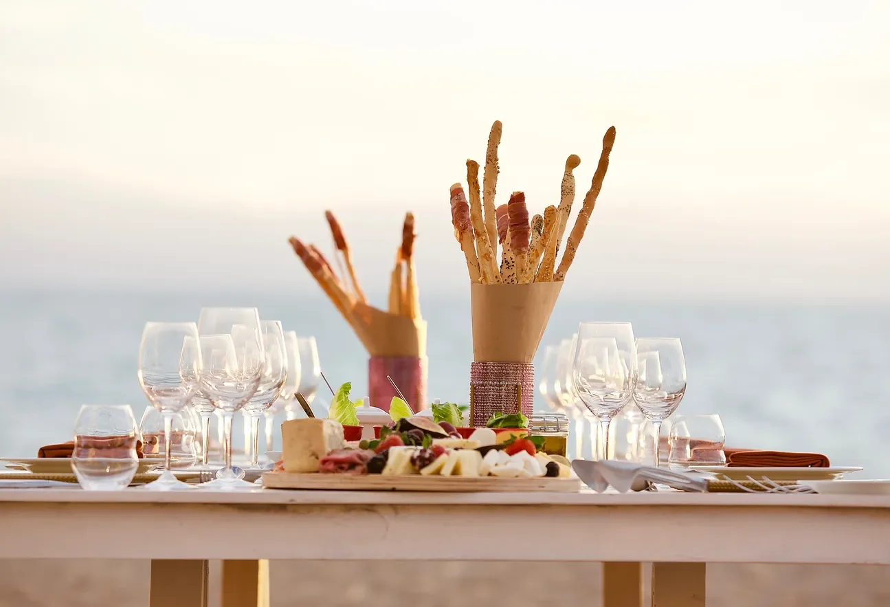Elegant beach wedding reception table setting in Puerto Vallarta, featuring a cheese and meat platter and breadsticks.
