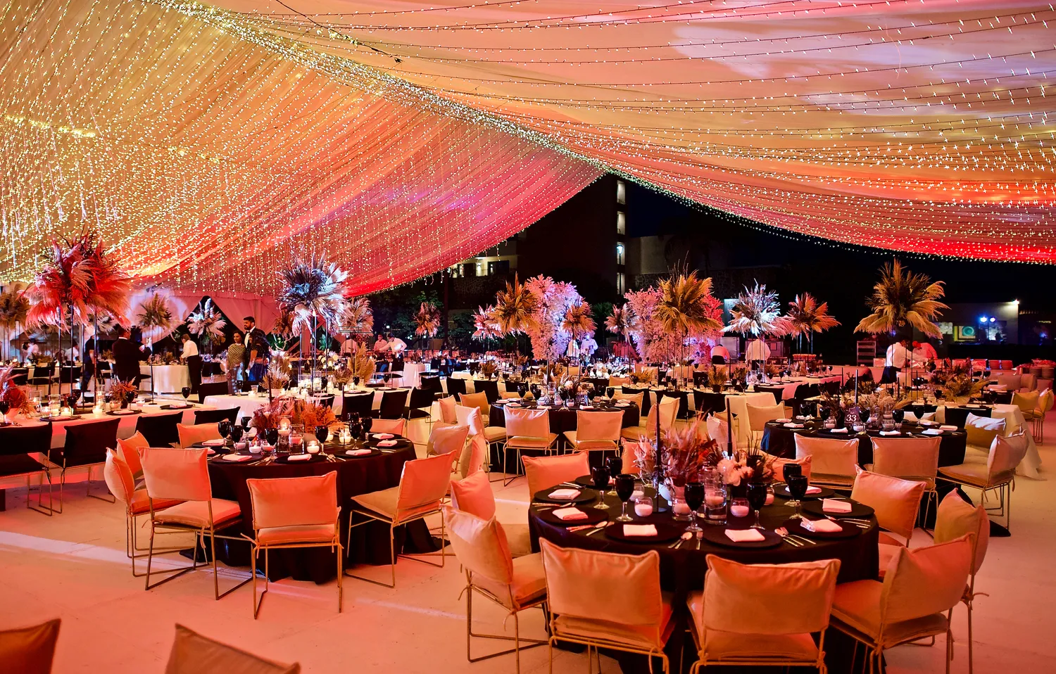 Elegant destination wedding reception at Marriott Puerto Vallarta, featuring round tables, warm lighting, and pampas grass centerpieces.