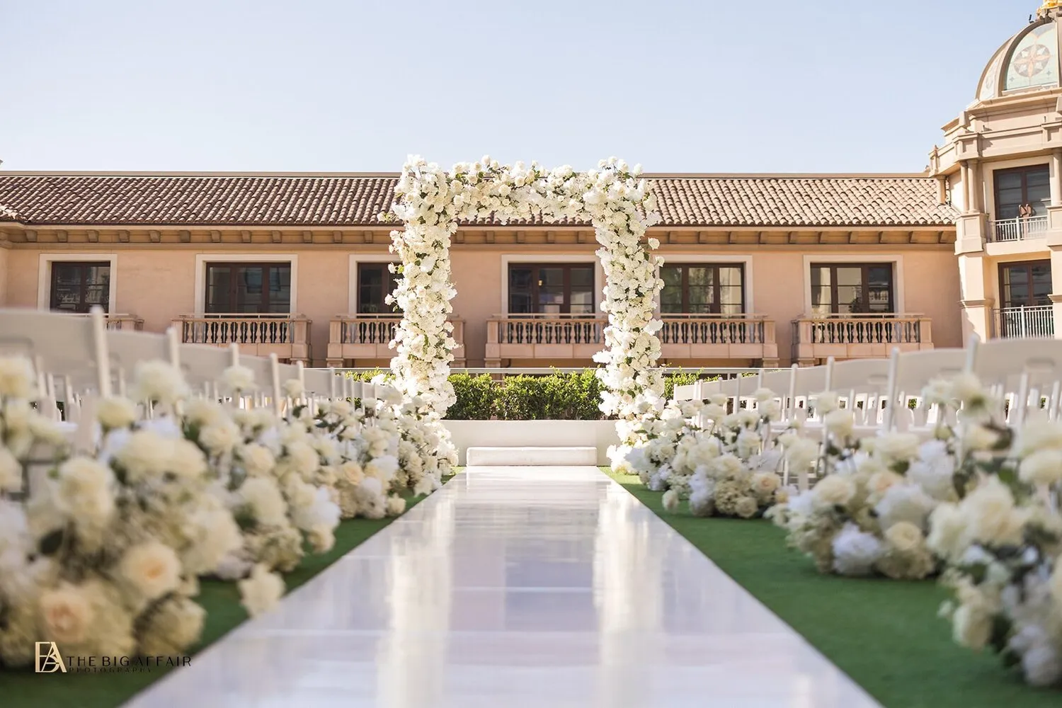 Elegant wedding ceremony setup at the Maybourne Beverly Hills, featuring a white floral arch and aisle.