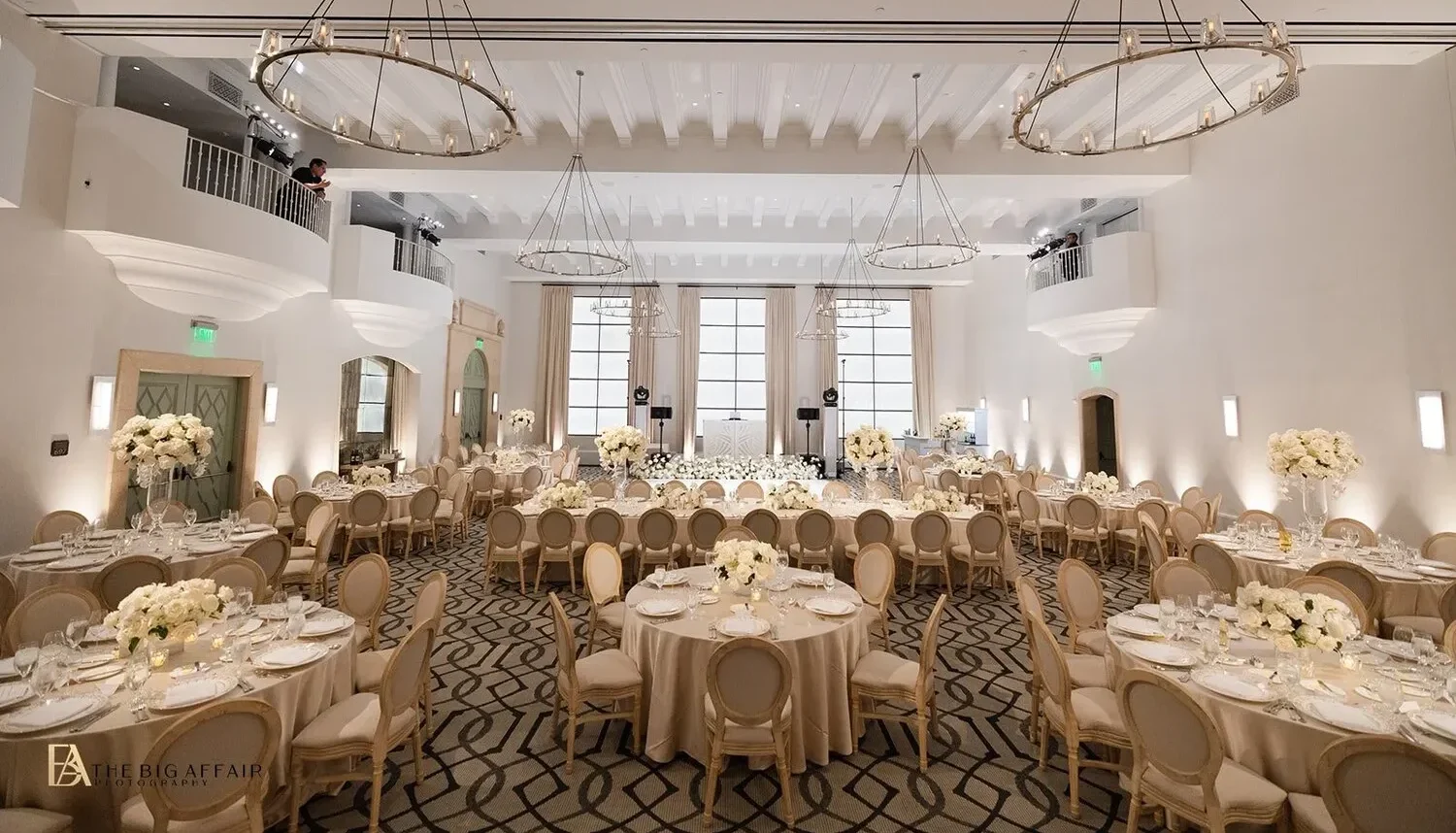 Elegant wedding reception at the Maybourne Beverly Hills, featuring round tables, beige chairs, and white floral centerpieces.