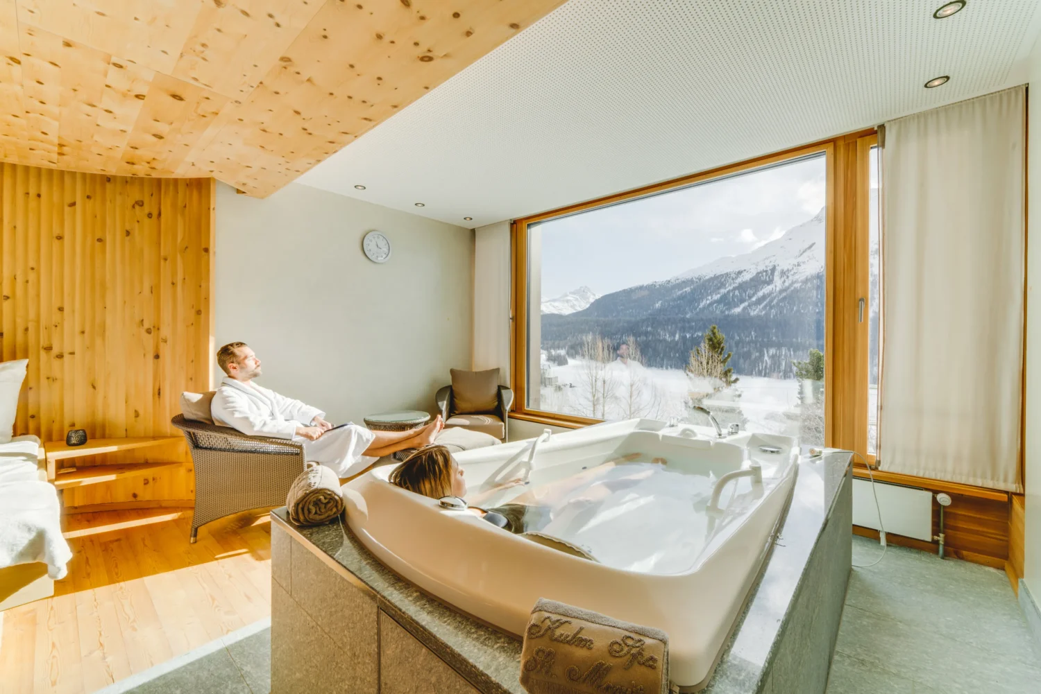 Couple relaxing in a luxury resort suite with a private hot tub and mountain view.