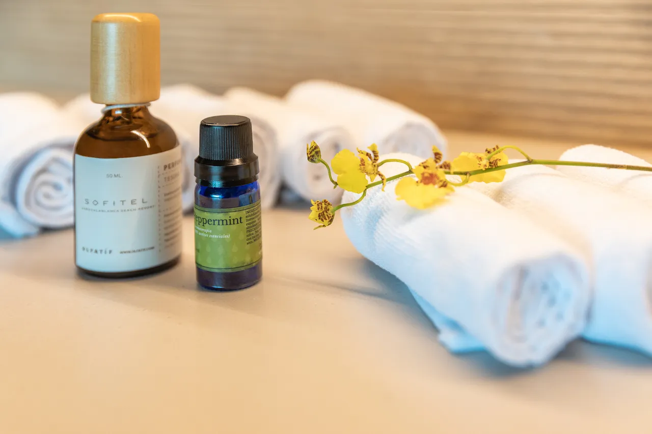 Rolled white towels, peppermint essential oil, and Sofitel-branded aromatherapy oil. Luxury resort amenities.