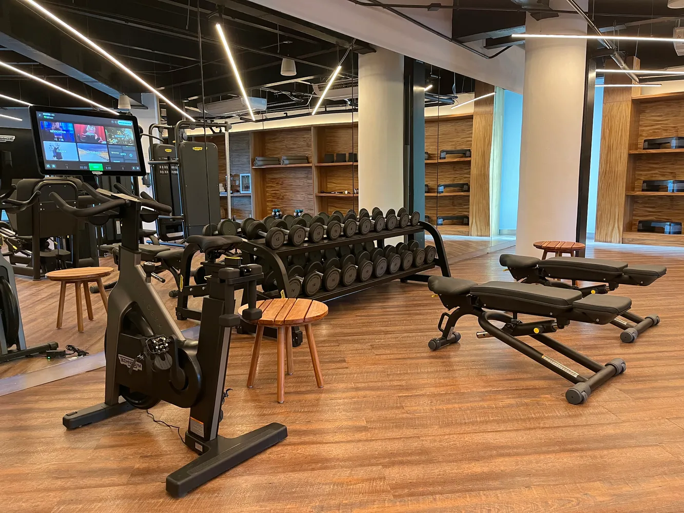 Modern gym at Almare Isla Mujeres resort with exercise bikes, weight rack, and adjustable benches.