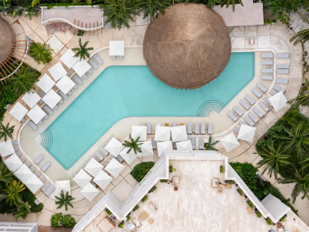 Aerial view of Almare Isla Mujeres resort pool, featuring lounge chairs and umbrellas. Perfect for a luxury vacation or destination wedding.