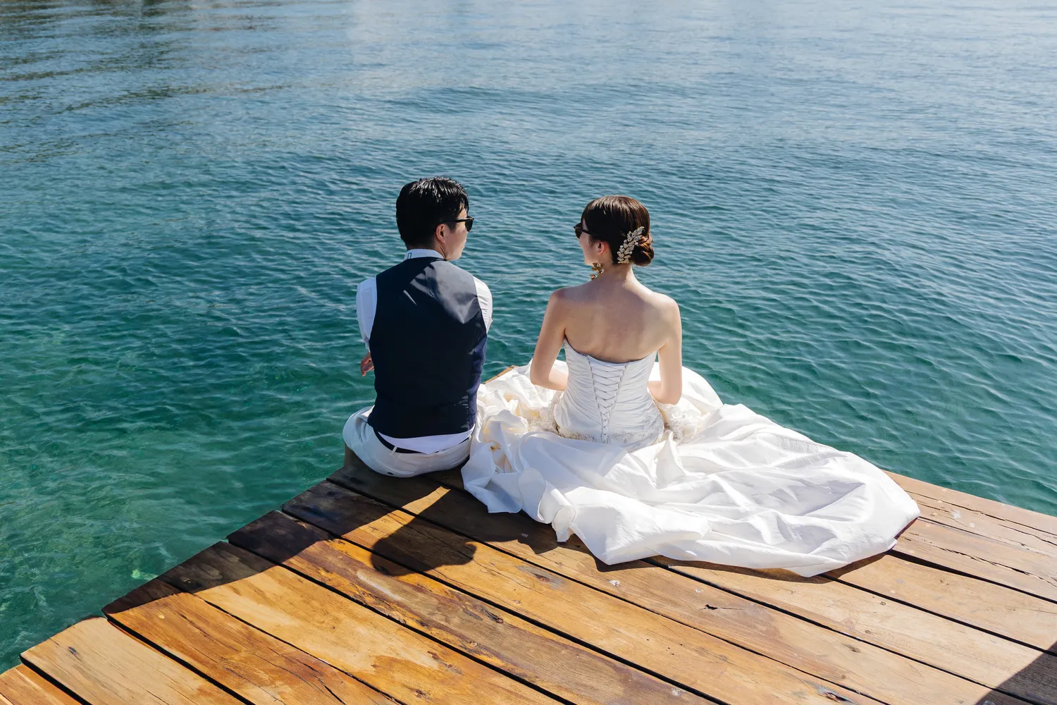 Bride and groom sit on a dock overlooking the ocean at their Almare Isla Mujeres wedding.