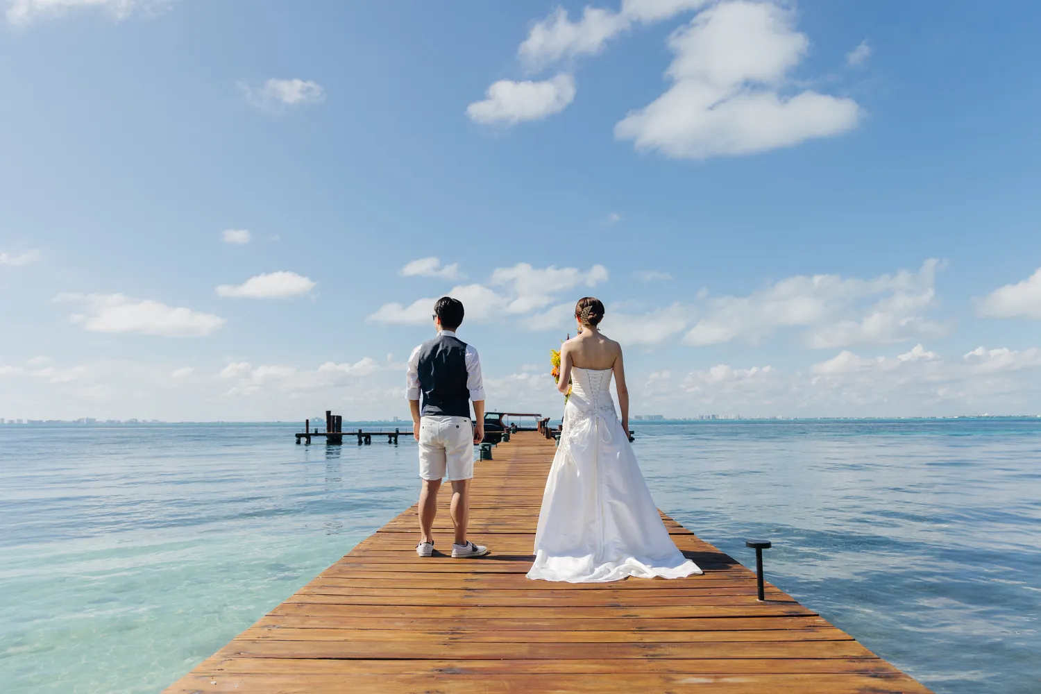 Bride and groom on a wooden dock overlooking the ocean at Almare Isla Mujeres for their wedding.