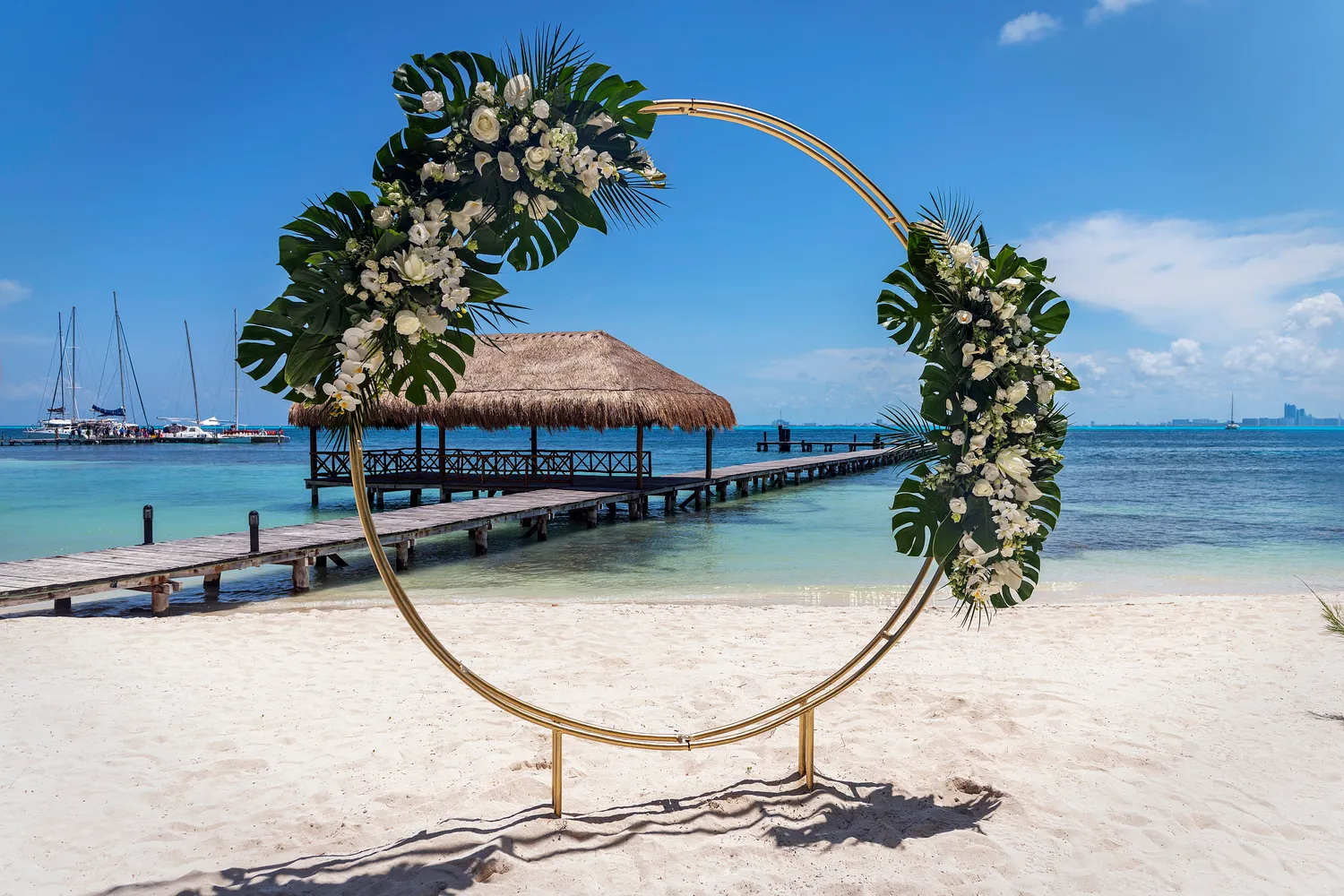 Beach wedding ceremony setup at Almare Isla Mujeres; floral arch on white sand.