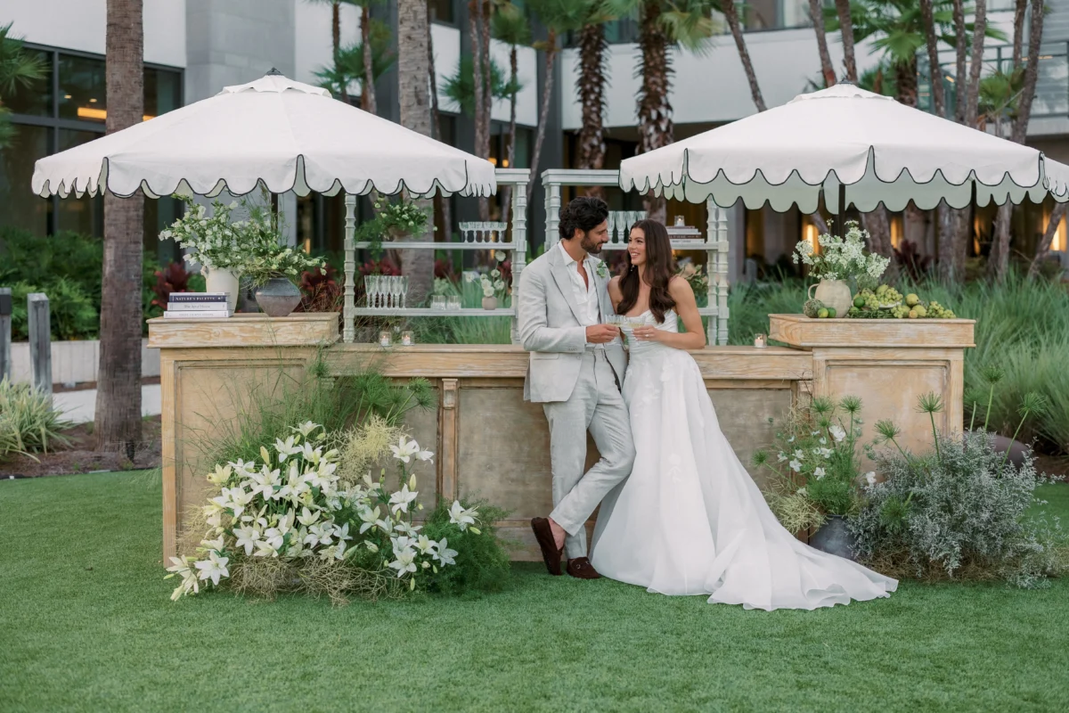 Elegant couple at a luxury destination wedding bar, enjoying champagne. Luxury destination wedding planning.