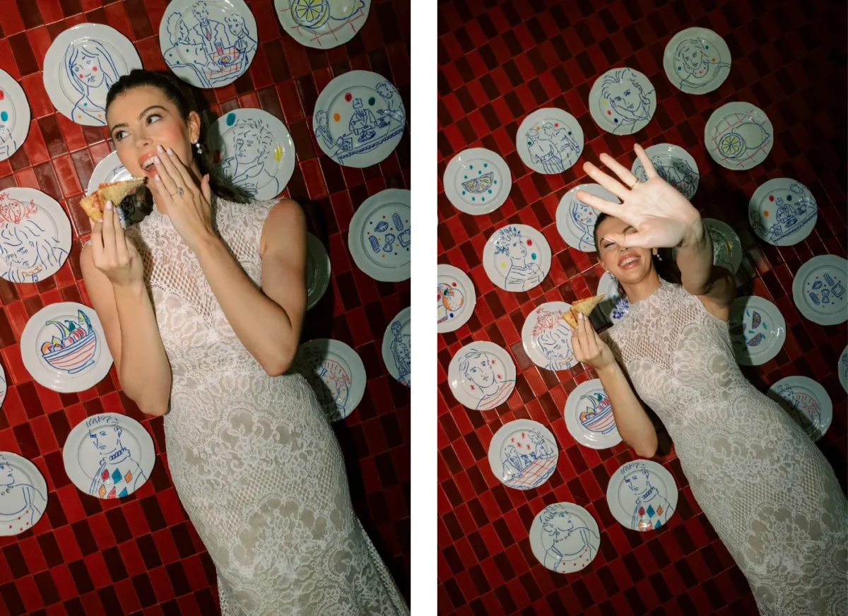 Bride in lace wedding dress enjoys pizza against a red tile wall decorated with plates at Conrad Orlando.
