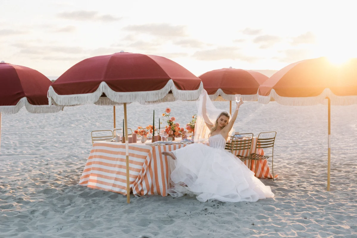 Bride celebrates at a luxury destination wedding reception on the beach with orange and white decor.