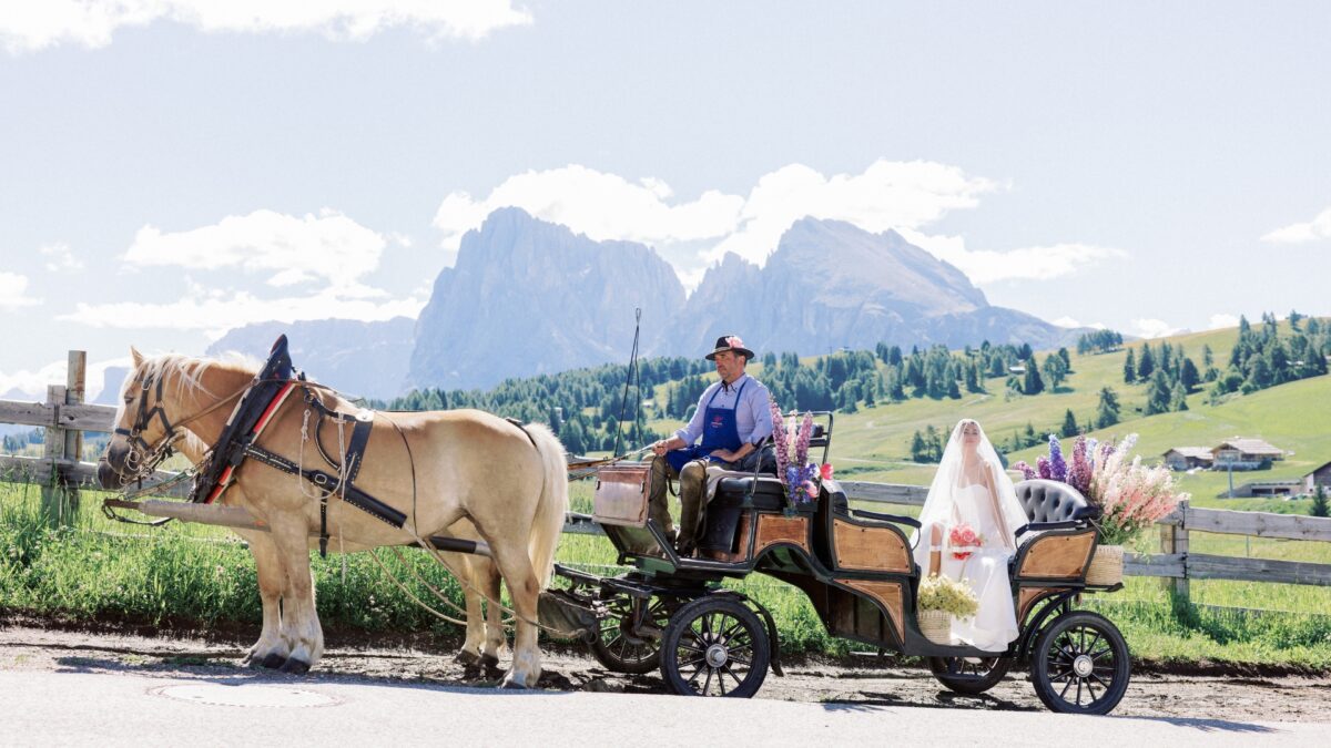 Bride in horse-drawn carriage with mountain backdrop