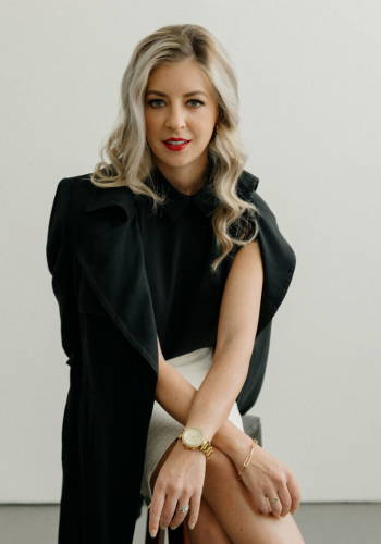 Woman in black top with blonde hair sitting confidently