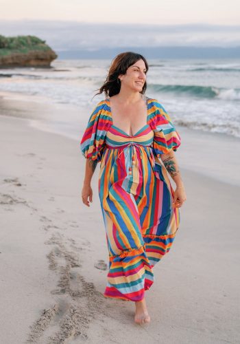Woman in colorful dress walking barefoot on a sandy beach