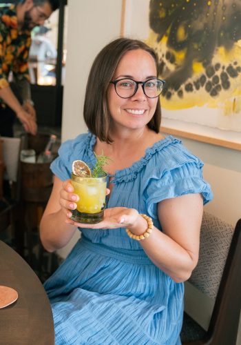 Woman in blue dress holding a cocktail at a cafe